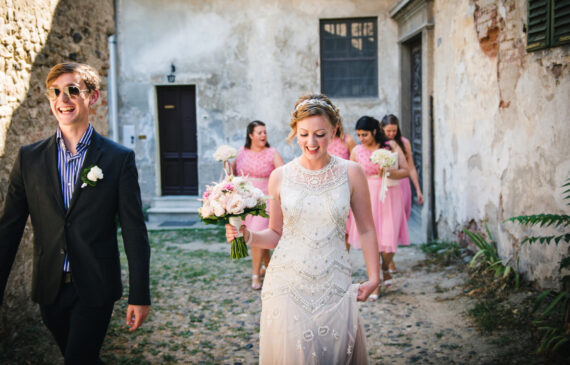 la sposa e le sue damigelle camminano verso il luogo della cerimonia al Castello di San Sebastiano da Po