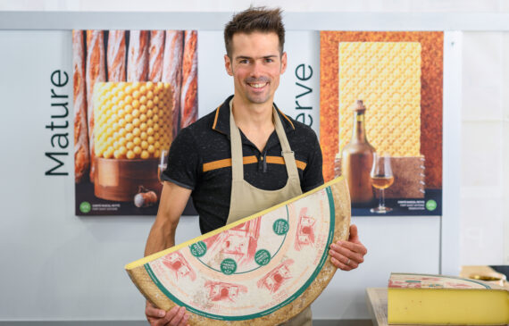 un uomo tiene tra le mani una forma di formaggio