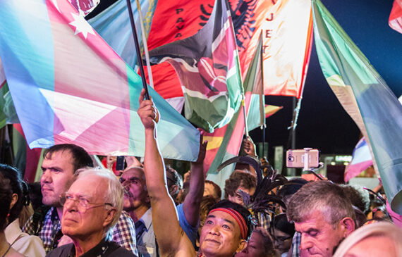 Un uomo in abiti tradizionali agita una bandiera durante una manifestazione pubblica
