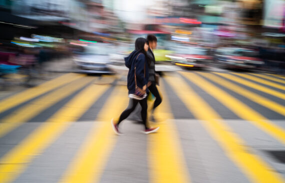 due persone passeggiano su delle strisce pedonali ad Hong Kong