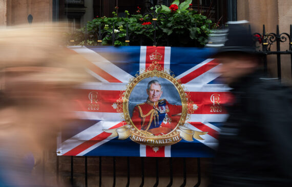 Due persone camminano davanti ad una bandiera raffigurante Re Carlo III a Londra£
