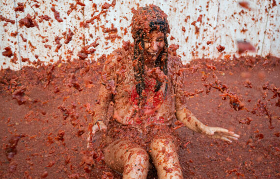 Una ragazza ride mentre pezzi di pomodoro volano per aria durante il festival La Tomatina, in Spagna