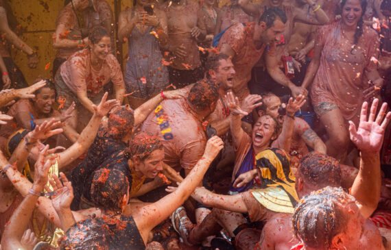 Uomini e donne pieni di salsa di pomodoro ridono e ballano durante il festival la tomatina a Buñol