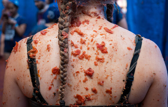 La schiena di una ragazza piena di salsa e di pezzi di pomodoro durante la tomatina in spagna