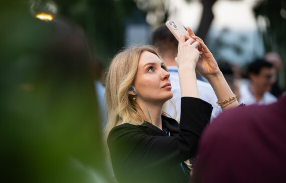 Una ragazza fotografa con il telefonino rivolto verso il cielo