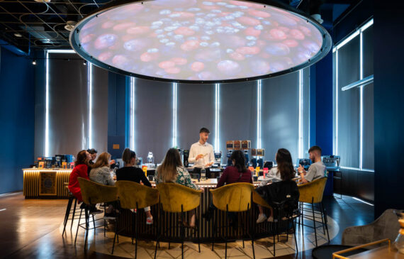 un barista mostra il metodo di preparazione di un caffè ad un gruppo di turisti