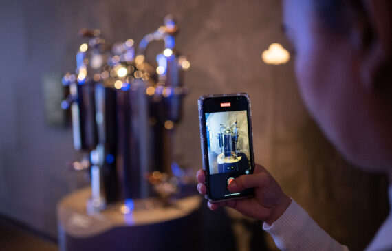 una ragazza fotografa con il telefono una macchina del caffè d'epoca