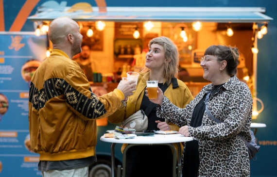 Tre ragazzi giovani fanno un brindisi davanti ad una birreria