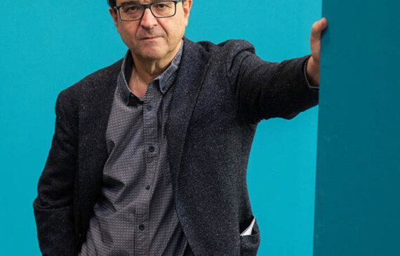 Ritratto fotografico a Torino dello scrittore spagnolo Javier Cercas su sfondo blu.