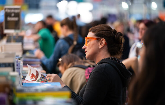 Una donna consulta un libro in esposizione al salone del libro di Torino