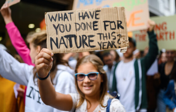 Una ragazza tiene tra le mani un cartello che protesta contro il cambiamento climatico durante una manifestazione a Torino