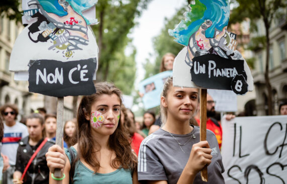 Due ragazze reggono cartelli contro il cambiamento climatico durante una manifestazione a Torino