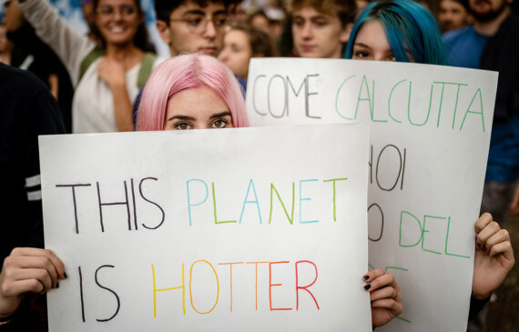 Due ragazze reggono cartelli contro il cambiamento climatico durante una manifestazione a Torino
