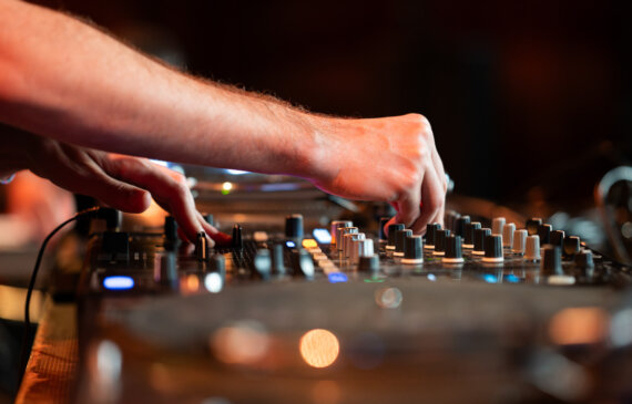 Una mano fotografata da molto vicino mentre controlla un mixer audio