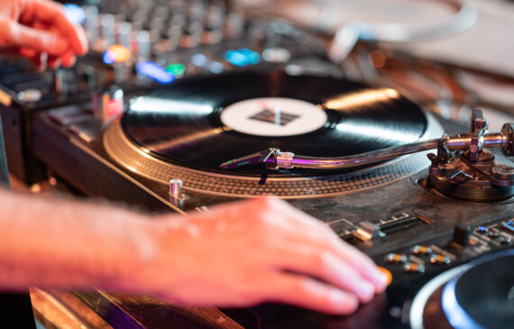 Un giradischi e un dettaglio di due mano che lo controllano durante lo sleep concert alle ogr Torino