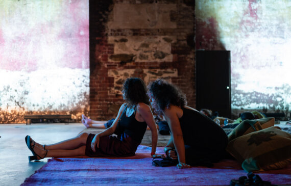 due donne ascoltano musica dal vivo seduta su dei tappeti colorati