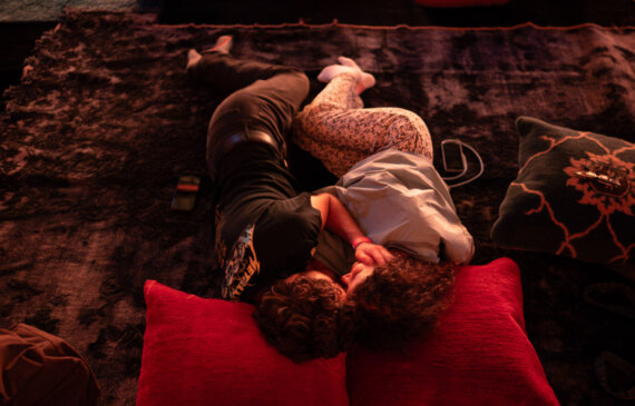 Due persone si abbracciano sdraiate su tappeti mentre ascoltano un concerto di musica rilassante alle ogr