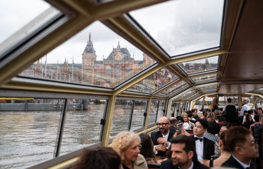 una barca viaggia tra i canali di Amsterdam con passeggeri eleganti a bordo
