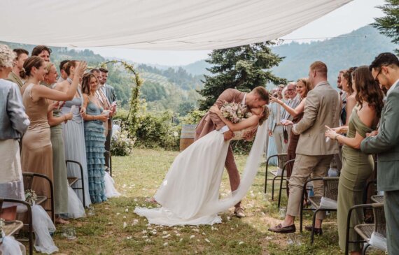 Due sposi si baciano dopo la cerimonia, mentre gli invitati applaudono