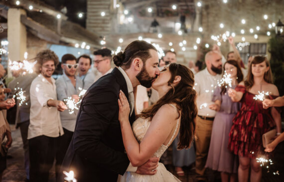 Gli sposi si baciano mentre gli invitati agitano stelline luminose