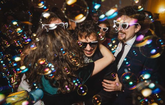 Uno sposo abbraccia una invitata durante la festa di un Matrimonio tra le bolle di sapone