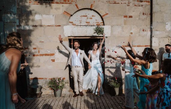 Due sposi escono felici dalla chiesa mentre gli invitati festeggiano