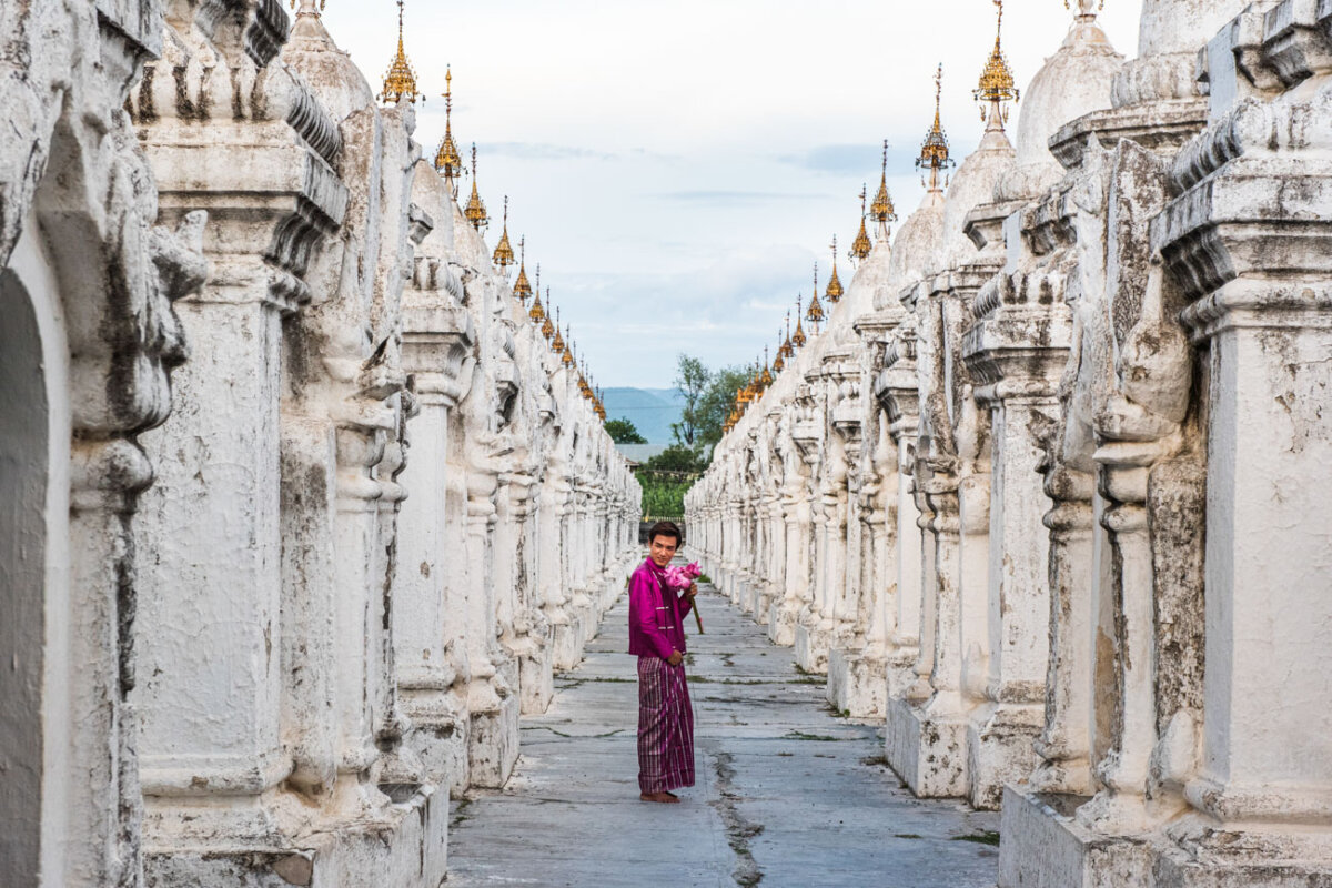 un ragazzo vestito in abito tradizionale tiene in mano un mazzo di fiori in un tempio in myanmar