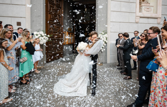 A couple of newlyweds kisses in front of a church during their destination wedding in Italy